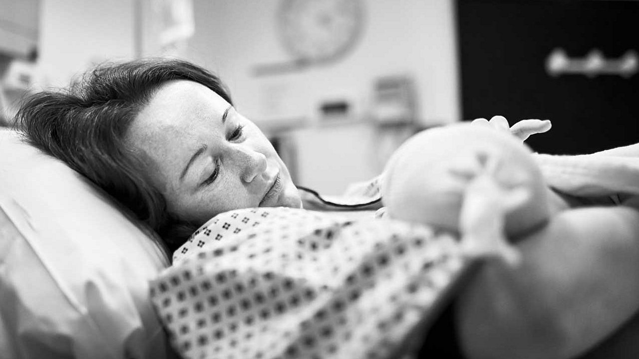 Schwarz-Weiß-Aufnahme der Mutter, die ihr Neugeborenes direkt nach der Entbindung hält