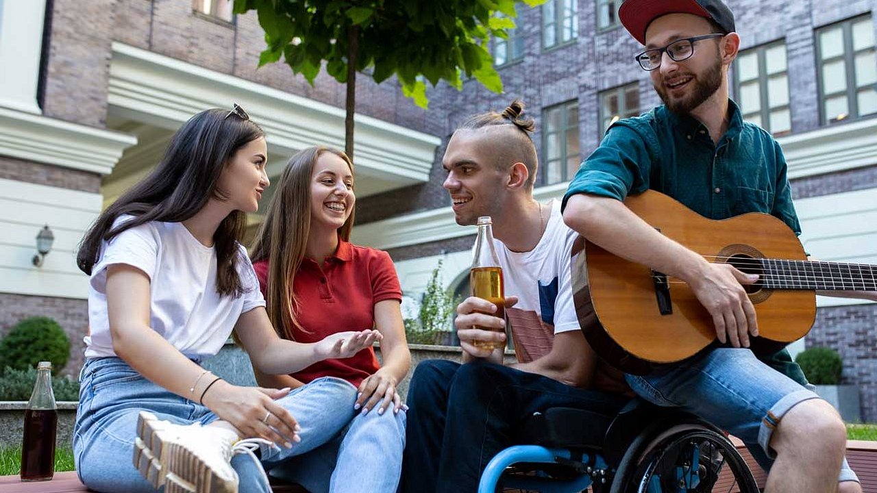 4 junge Menschen sind unterwegs. Einer hält eine Gitarre. 