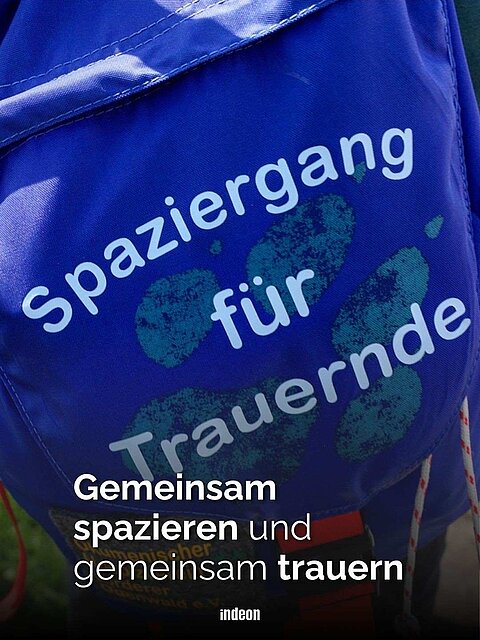 Ein blauer Rucksack mit weißer Schrift: Spaziergang für Trauernde. Text: Gemeinsam spazieren und gemeinsam trauern