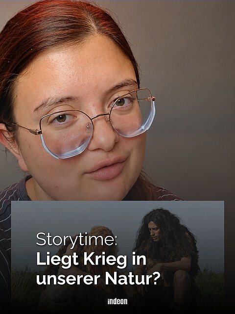 Eine Frau mit Brille und dunklen Haaren blickt in die Kamera vor grauem Hintergrund. Unten Portrait einer steinzeitlichen Szene, zwei Menschen in Fellkleidung sitzen auf Steinen. Dazu der Text: "Storytime: Liegt Krieg in unserer Natur?"