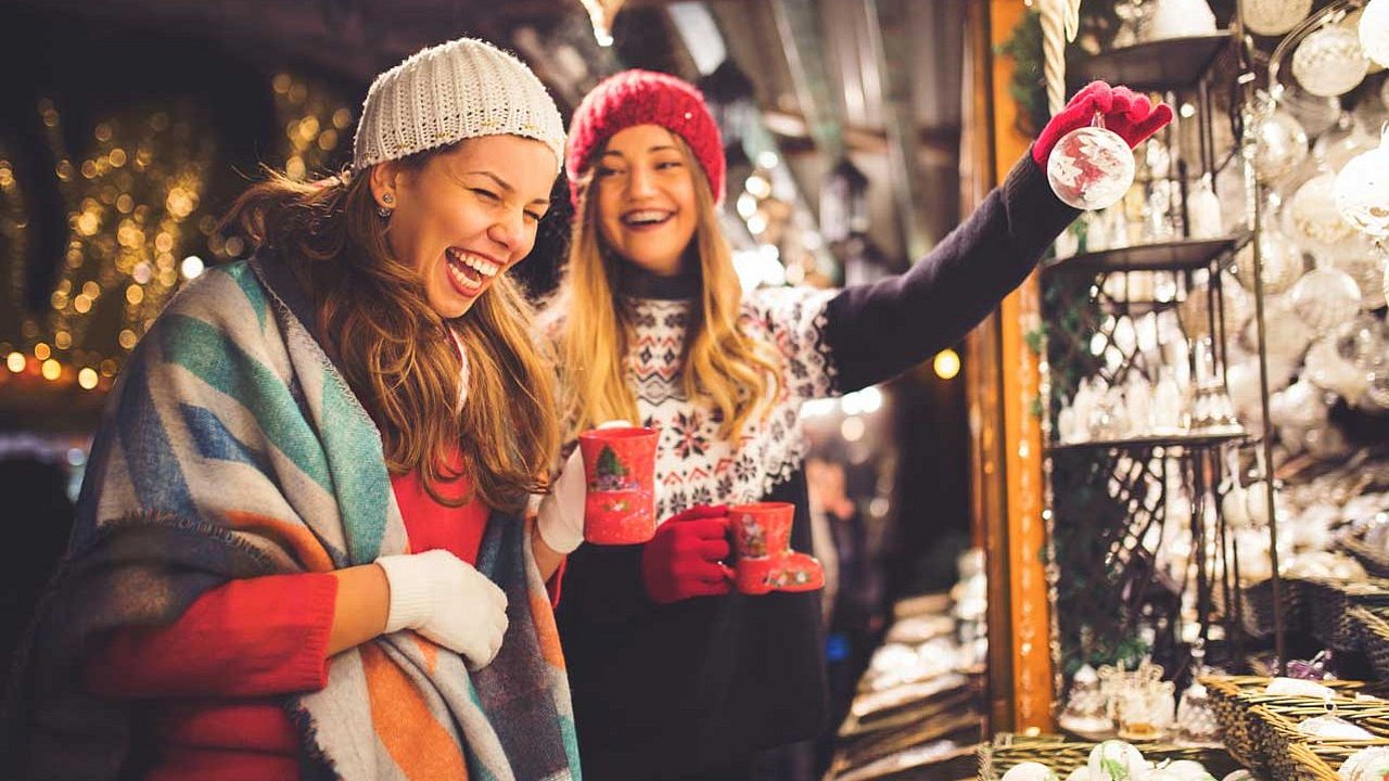 2 Frauen auf dem Weihnachtsmarkt schauen sich Weihnachtskugeln an