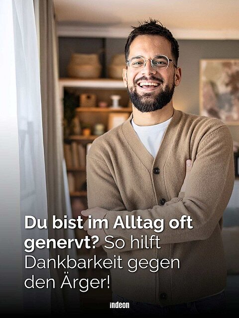 Lächelnder Mann mit Brille und Bart in Wohnraum, Text: „Du bist im Alltag oft genervt? So hilft Dankbarkeit gegen den Ärger!“