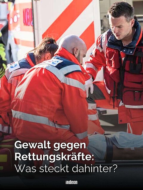 Rettungskräfte in roter Kleidung betreuen eine Person auf einer Trage vor einem Rettungswagen. Text: Gewalt gegen Rettungskräfte: Was steckt dahinter?