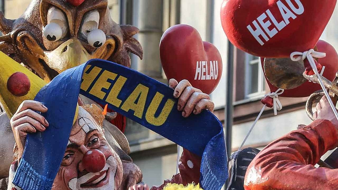 Fastnachtswagen: Eine der Figuren hält einen Schal, auf dem Helau steht