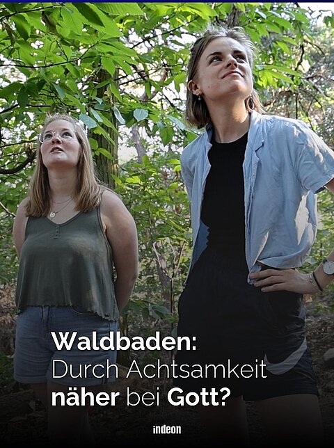 Zwei Frauen stehen beim Waldbaden in einem grünen Wald und blicken nach oben. Text im Bild: „Waldbaden: Durch Achtsamkeit näher bei Gott?“