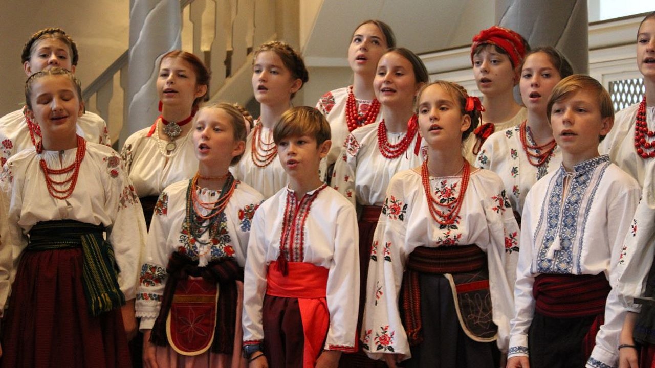 Ein Kinderchor mit ukrainischen Jungen und Mädchen singt Lieder in einer Kirche.