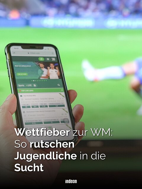 Zu sehen ist eine Textkachel. Im Hintergrun verschwommen ein Fernseher auf dem ein Fußballspiel gezeigt wird. Im Vordergrund ist eine hand zu sehen, die ein Smartphone hält auf dem eine SportwettenApp geöffnet ist. In weißer Schrift steht geschrieben: Wettfieber zur WM: So rutschen Jugendliche in die Sucht.