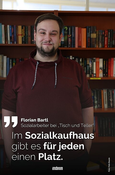 Florian steht vor einer Bücherwand. Er trägt einen weinroten Kapuzenpulli und lächelt in die Kamera. Es ist ein Zitat von ihm auf dem Foto zu sehen: „Im Sozialkaufhaus gibt es für jeden einen Platz.“ 
