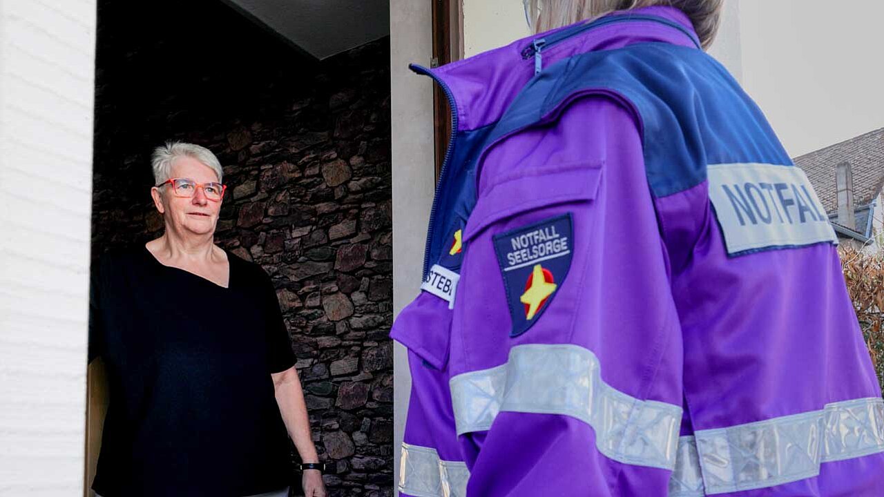 Marika hat die Türe geöffnet. Vor der Türe steht eine Notfallseelsorgerin in ihrer lila Jacke.