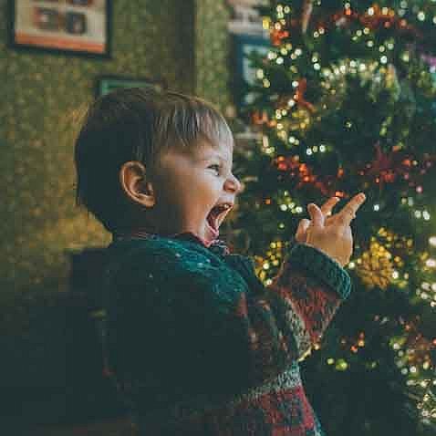 kleiner Junge freut sich unterm Tannenbaum