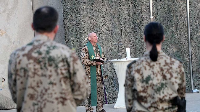 Pfarrer in Militärkluft zwischen Soldaten