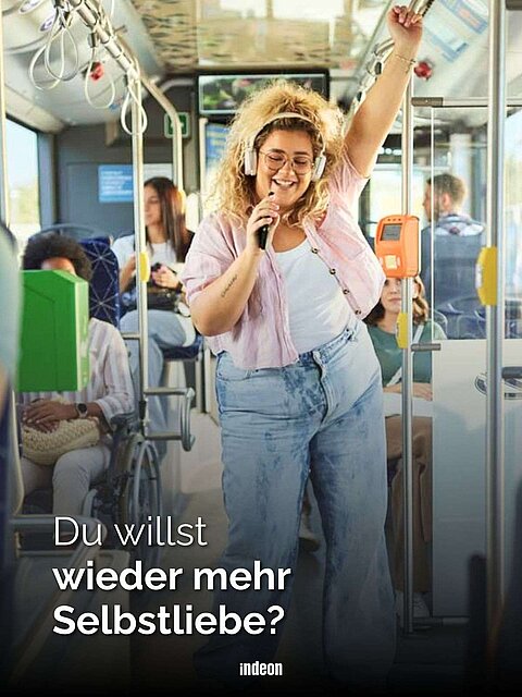 Eine blonde Frau tanzt glücklich in einem Bus. Text: Du willst wieder mehr Selbstliebe?