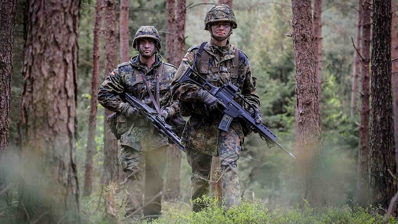 Zwei Soldaten gehen mit Waffen durch den Wald
