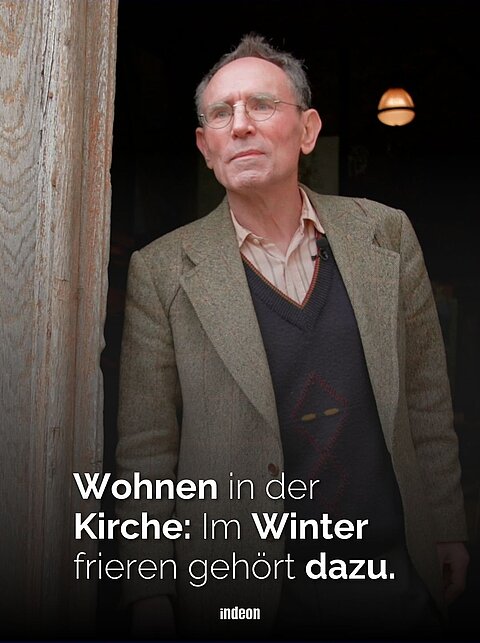 Der Künstler Benedikt Forster steht angeleht in der Tür zu kirche. Der ältere Mann trägt Sakko, Hemd und Pullover. 
