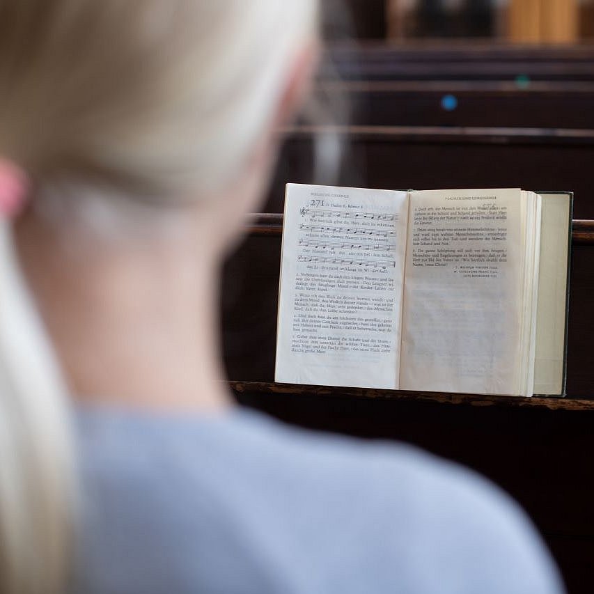 Ein Mädchen sitzt in einer Kirchenbank