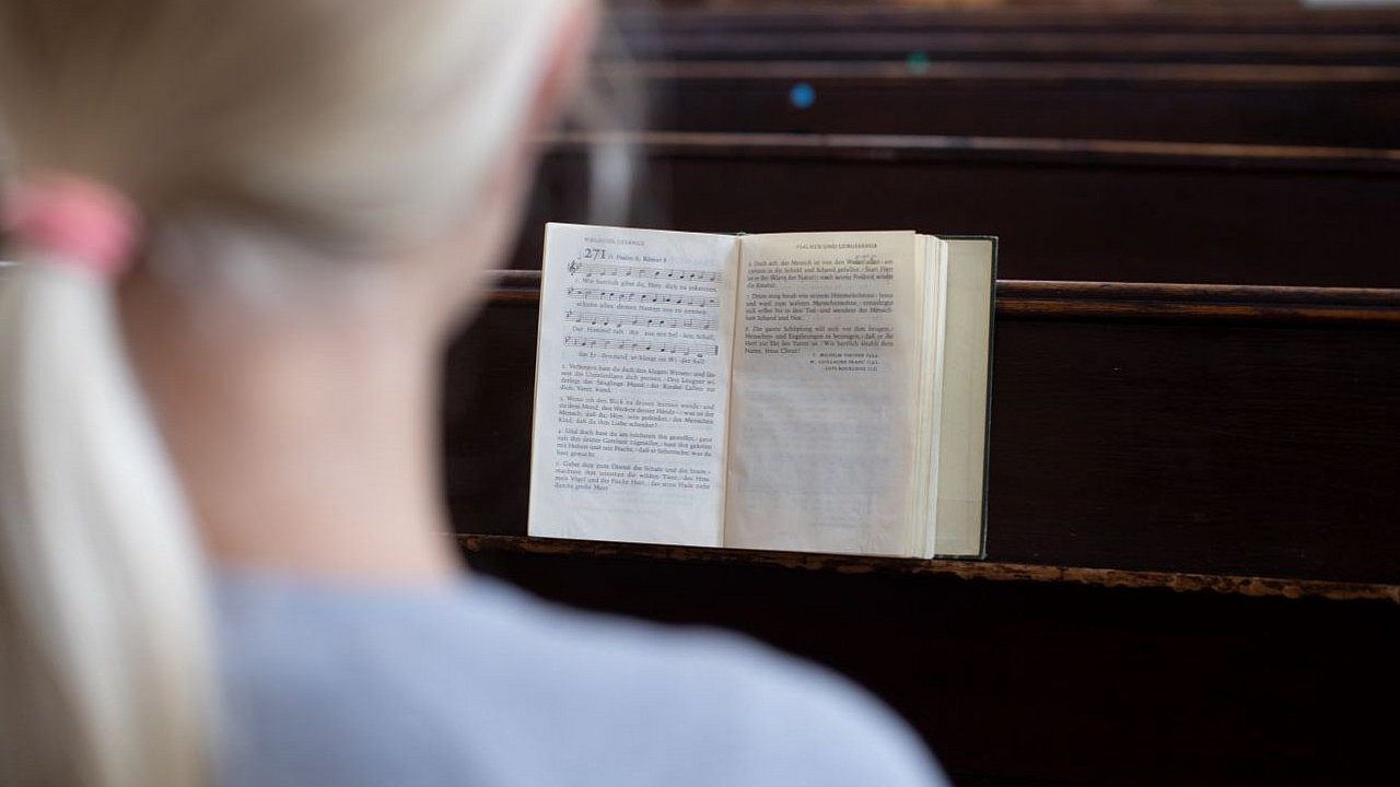 Ein Mädchen sitzt in einer Kirchenbank