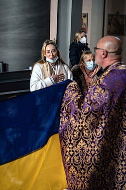 Frau steht in der Kirche, singt und hält die Hand aufs Herz