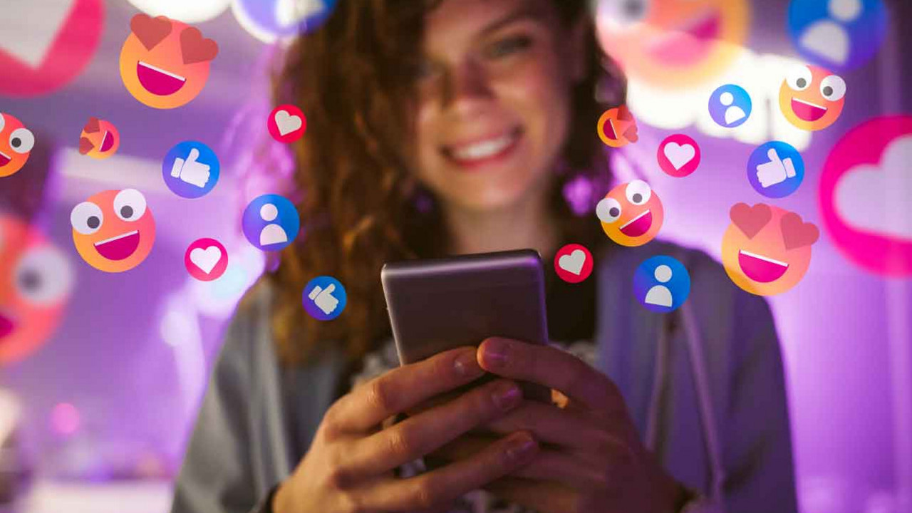 Glückliche junge Frau, die ihr Telefon benutzt, um mit sozialen Medien zu interagieren