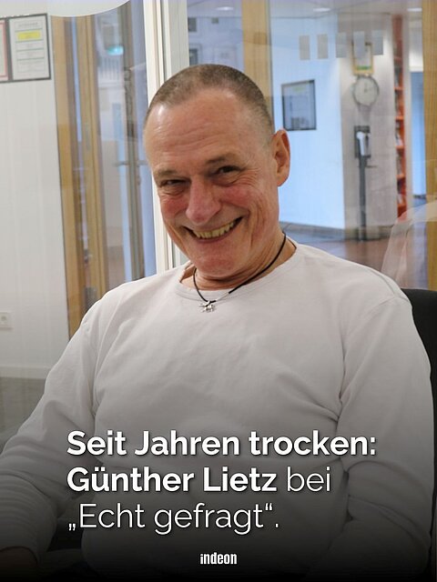 Ein Mann mit kurzgeschorenen grauen Haaren und weißem Shirt lächelt. Text: Seit Jahren trocken: Günther Lietz bei „Echt gefragt“