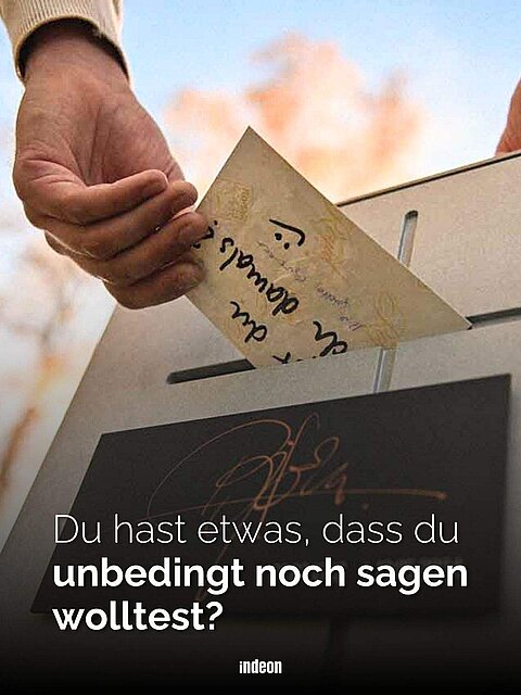 Ein Mensch wirft einen handgeschriebenen Brief in einen Briefkasten-Grabstein. Text: 'Du hast etwas, dass du unbedingt noch sagen wolltest?'