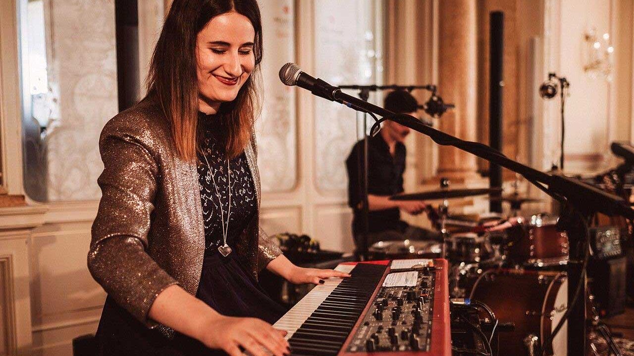 Julia Buch steht an einem roten E-Piano und vor einem Mikrofon