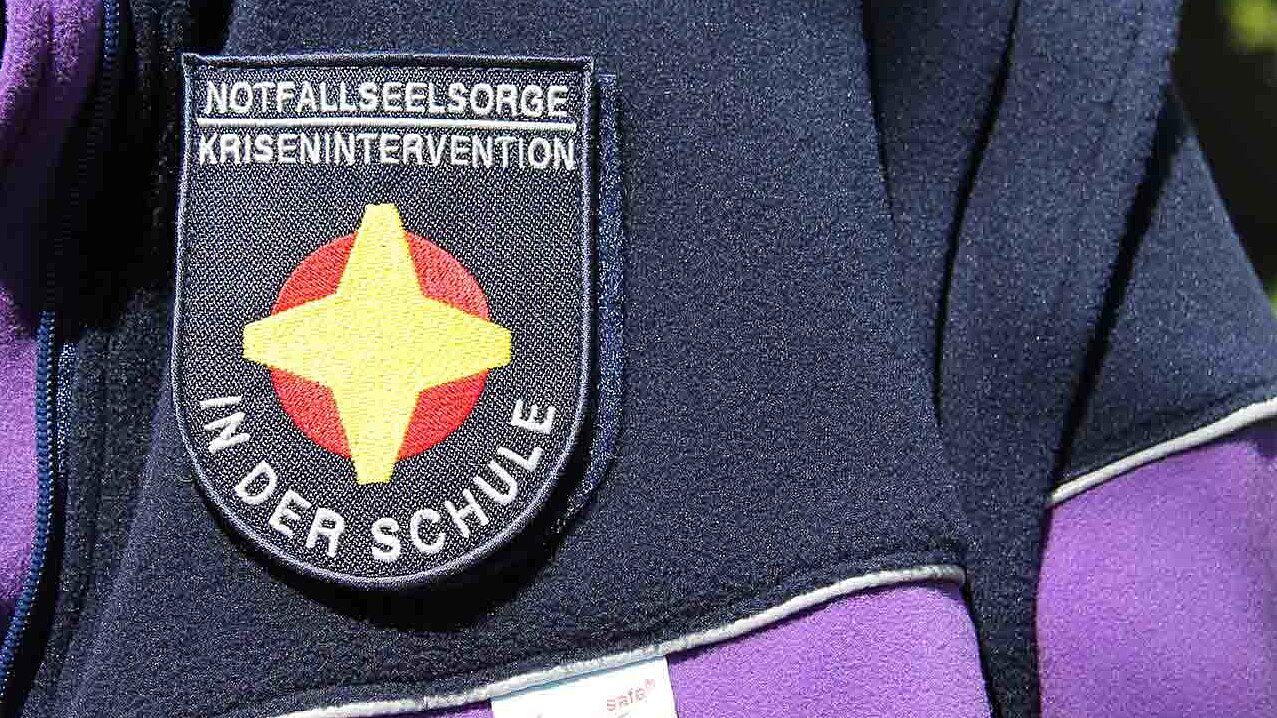 Aufnäher "Notfallseelsorge in der Schule" auf einer lila Notfallseelsorge-Jacke