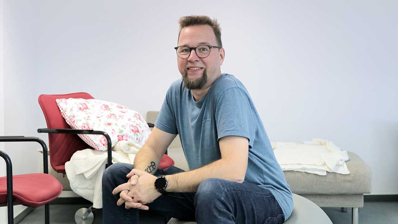 Seba sitzt in einem Raum auf einem grauen großen Gummiball.