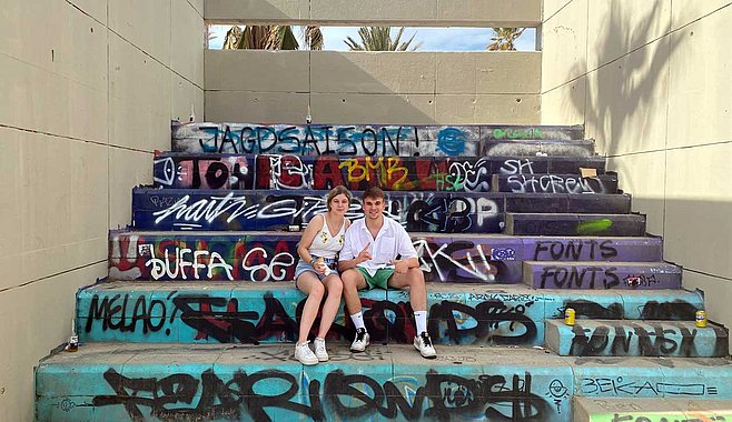 Rosalie und Simon sitzen auf den bunten Stufen in Barcelona