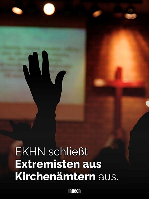 Eine erhobene Hand vor einem Kirchenraum. Im Hintergrund Lichter und ein Kreuz. Text: EKHN schließt Extremisten aus Kirchenämtern aus