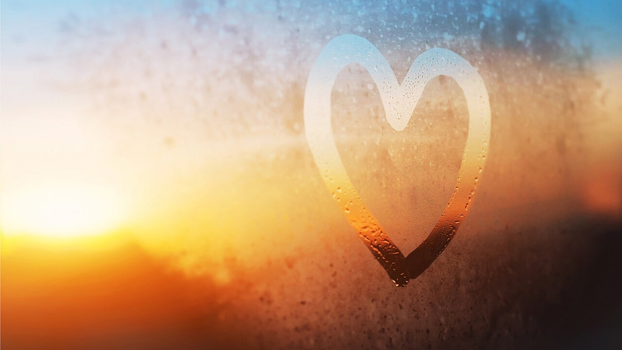 Herz auf Scheibe, Tau, Im Hintergrund ein Sonnenuntergang.