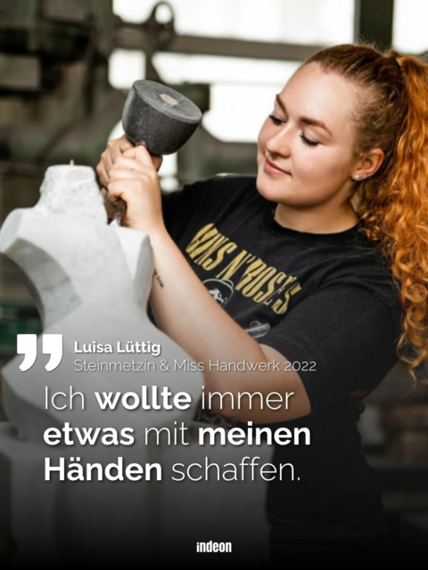 Auf dem Bild ist die junge Frau Luisa Lüttig zu sehen. Sie hat rotes langes Harr, welches zu einem Zopf gebunden ist. Sie hält den Kopf schräg und bearbeitet mit Hammer und Meißel einen hellgrauen Stein zu einer Skulptur.