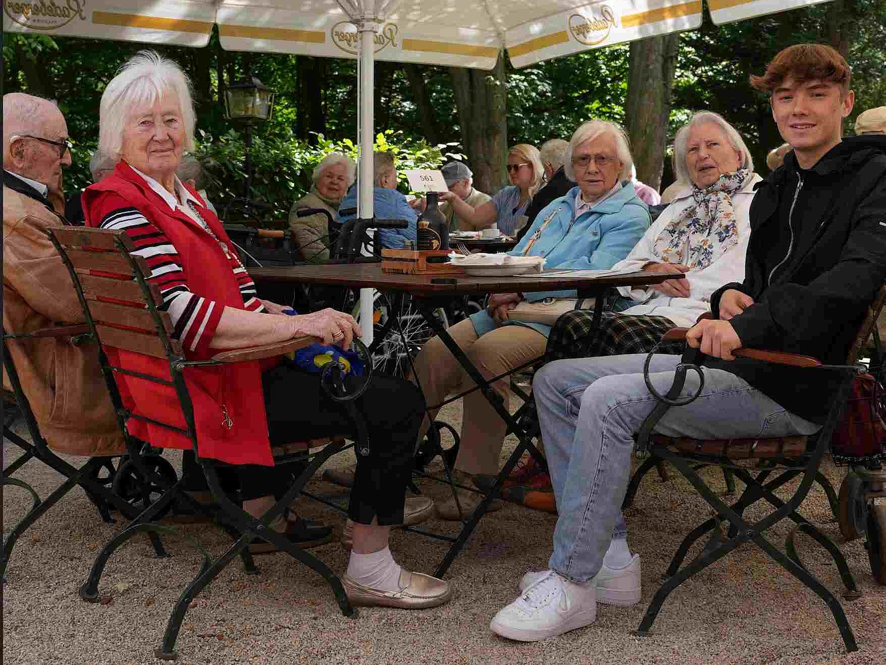 Max Löser schlüpft in die Rolle eines Altenbetreuers und sitzt mit Bewohnerinnen und Bewohnern des Haus Emmaus am Tisch.