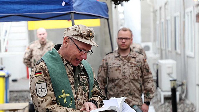 Pfarrer Aupperle in Tarnkleidung und mit der Bibel in der Hand 