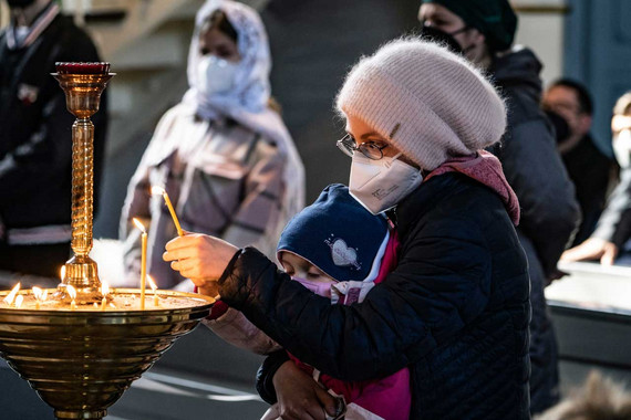 Frau mit Kind zündet Kerzen an