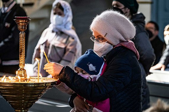 Frau mit Kind zündet Kerzen an