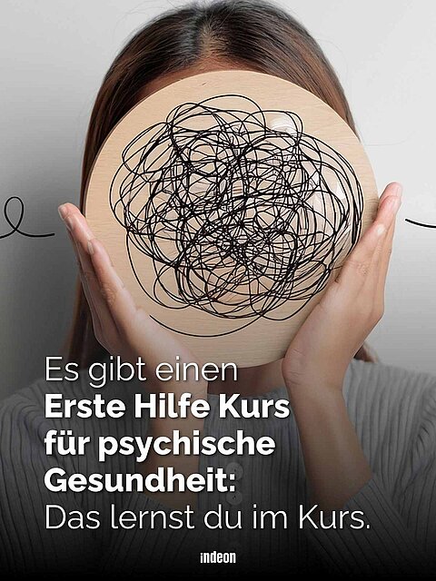 Person hält rundes Holzbrett mit schwarzem Wirrwarr vor das Gesicht, dazu Text: Es gibt einen Erste Hilfe Kurs für psychische Gesundheit: Das lernst du im Kurs.