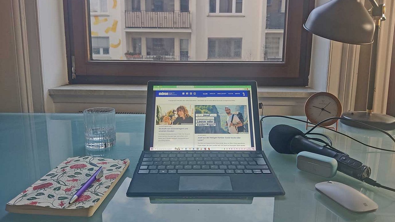 Fensterplatz: Das Home-Office von Redakteurin Charlotte Mattes, Laptop, Mikro, Block und Wasserglas stehen auf Glastisch.