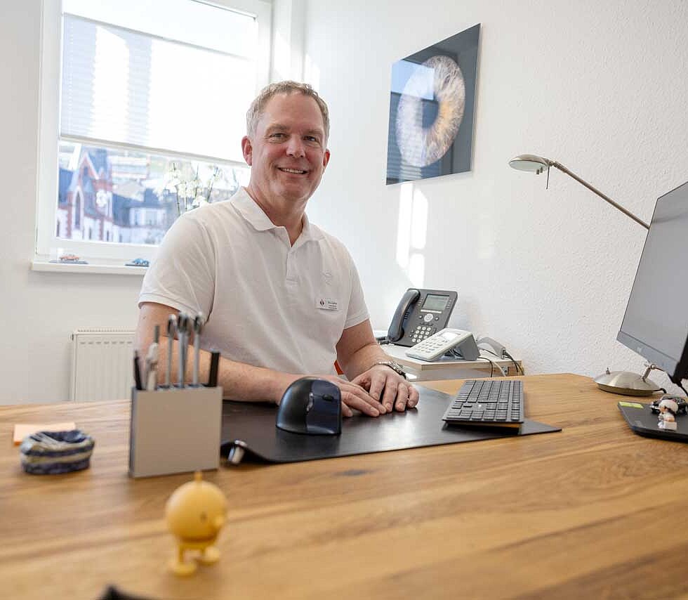 Lutz Lührs in seinem Behandlungszimmer am Schreibtisch. 