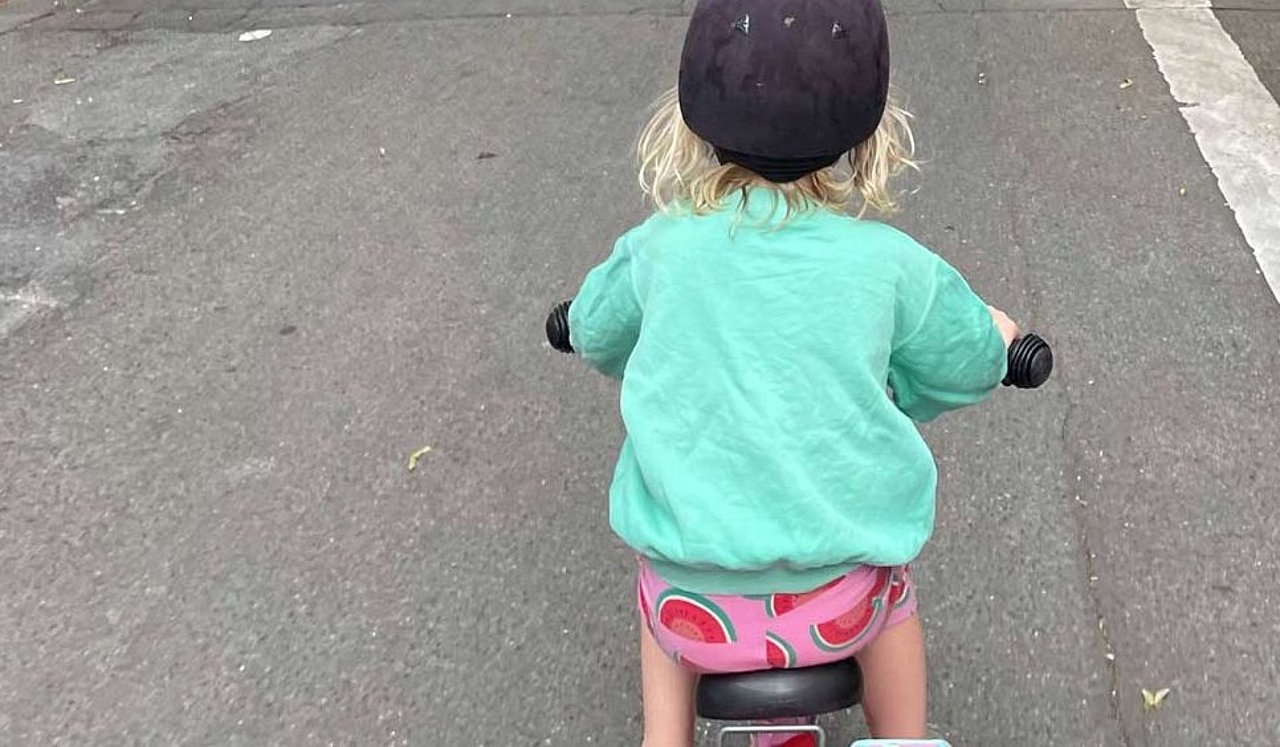 Karlas Tochter von Hinten auf einem Sattel. Man sieht nur Helm und blonde Locken darunter.