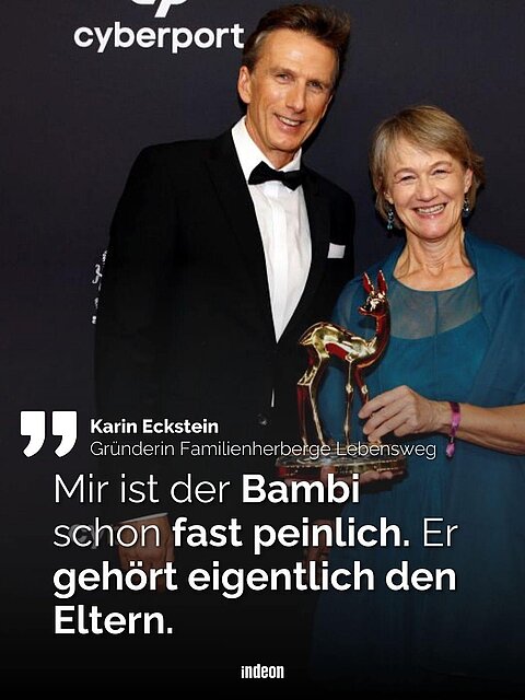 Zwei Personen vor einer schwarzen Fotowand. Sie halten einen Bambi in der Hand: einen Preis verliehen in der Kategorie "Stille Helden". Dazu der Text: Karin Eckstein. Gründerin Familienherberge Lebensweg. "Mir ist der Bambi fast schon peinlich. Er gehört eigentlich den Eltern."