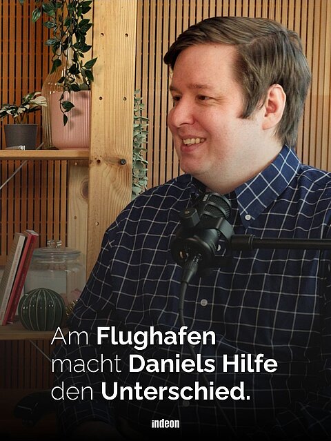 Daniel McMackin ist seit 2023 ehrenamtlich beim kirchlichen Sozialdienst am Frankfurter Flughafen aktiv. Im Podcst „echtgefragt“ erzählt er unter anderem davon, wwas ihn zu seiner Arbeit am flughafen motiviert, Auf dem Bild sitzt er in einem karrierten hemd vor dem Mikrofon und lächelt.