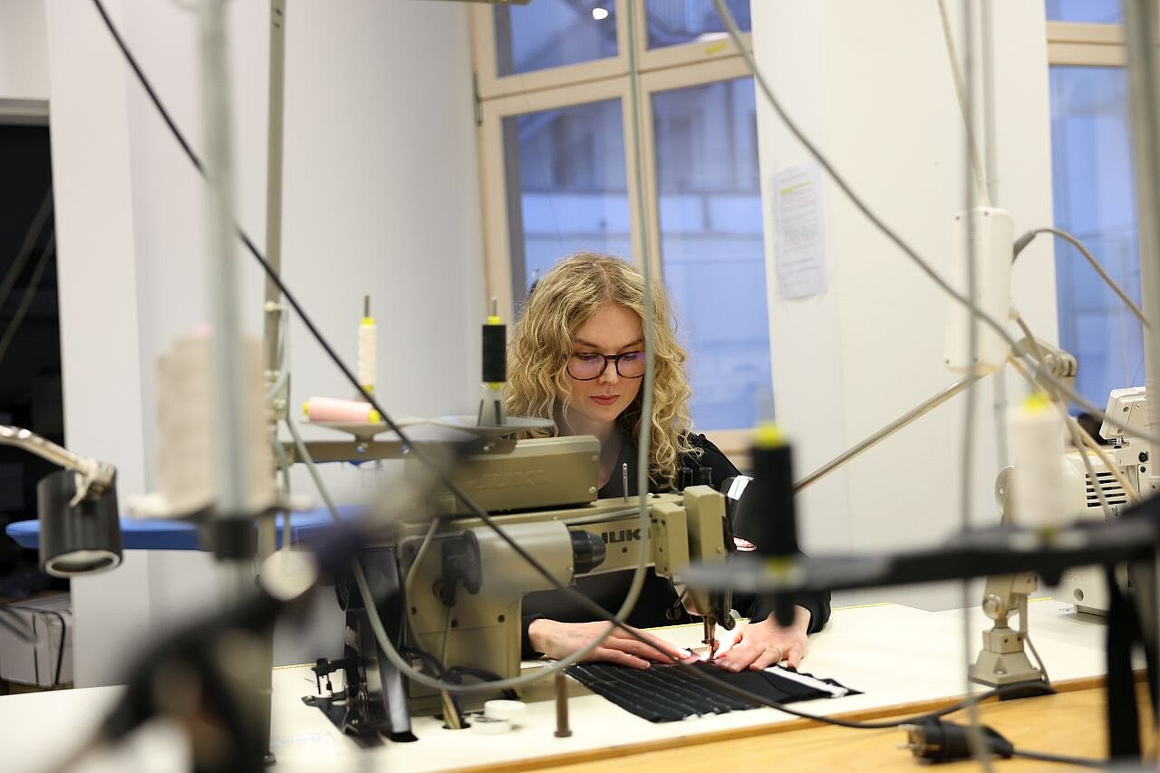 Claire sitzt in einer Werkstatt an einer Schreibmaschine