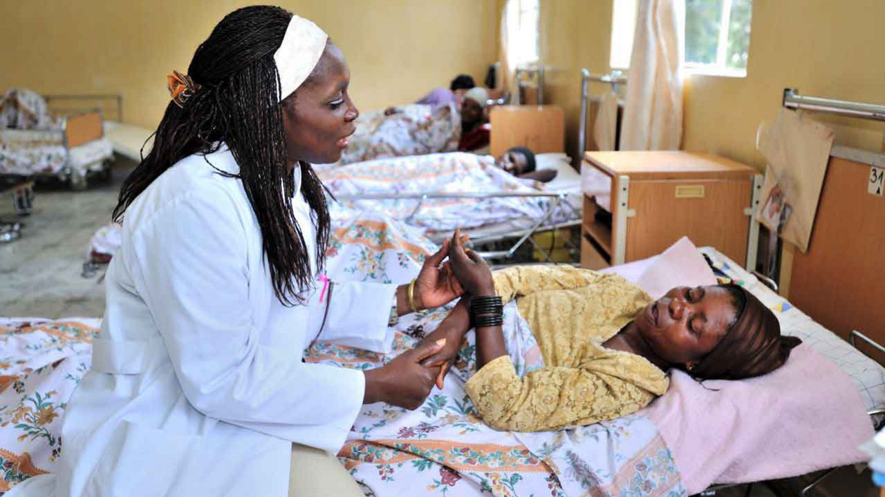 Eine Ärztin im Kongo sitzt am Bett einer Patientin und spricht mit ihr.