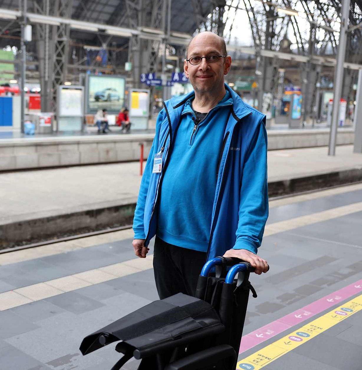 Leif Murawski steht neben einem Rollstuhl am Bahngleis 