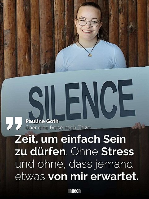 Eine Person hält ein Schild mit der Aufschrift "SILENCE" vor einem Hintergrund aus Holz. Darunter ist ein Zitat von Pauline Goth, das über eine Reise nach Taizé spricht: "Zeit, um einfach Sein zu dürfen. Ohne Stress und ohne, dass jemand etwas von mir erwartet."