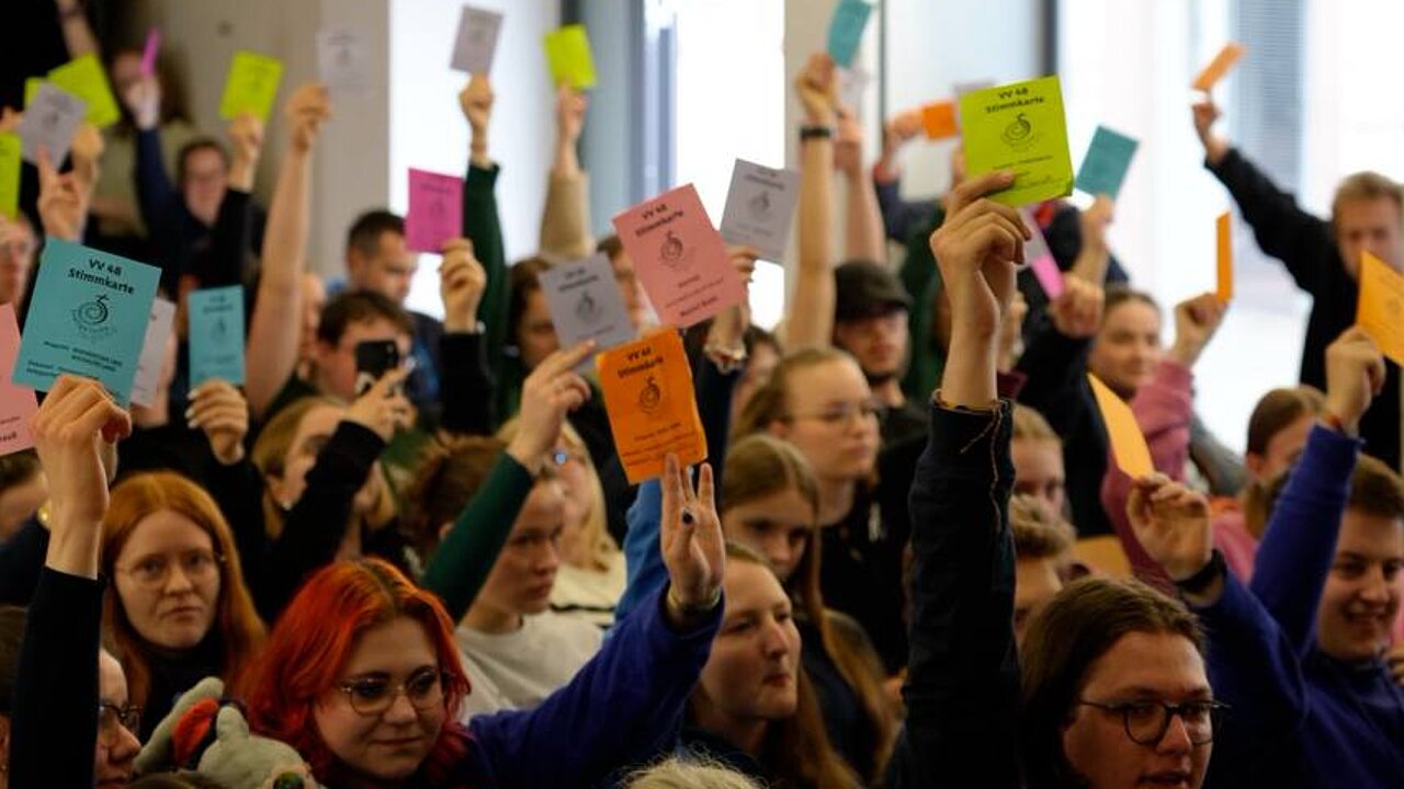 Junge Menschen mit Stimmzetteln bei einer Versammlung