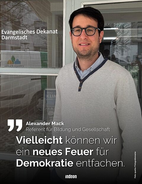 Das Bild zeigt Alexander Mack, Referent für Bildung und Gesellschaft beim Evangelischen Dekanat Darmstadt, vor einem Gebäude. Eine eingeblendete Aussage beschäftigt sich mit der Bedeutung von Demokratie.