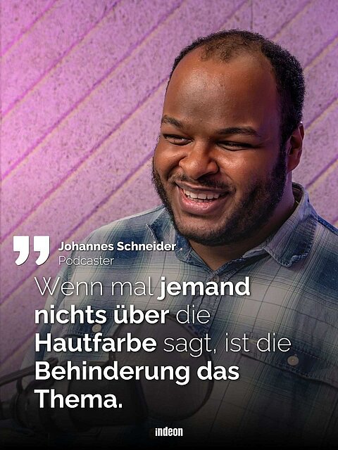 Lachender Schwarzer Mann mit freundlichem Lächeln vor pinkem Hintergrund. Text: Johannes Schneider. Podcaster. Wenn mal jemand nichts über die Hautfarbe sagt, ist die Behinderung das Thema.