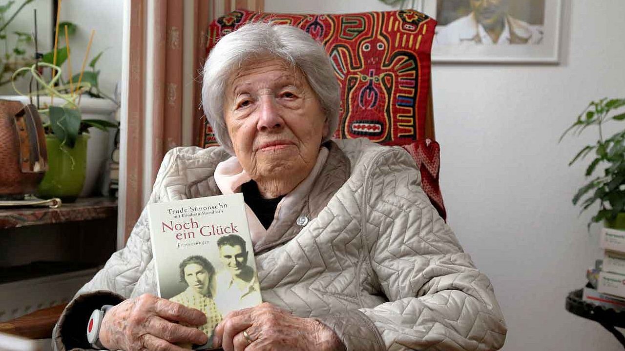 Holocaust-Überlebende Trude Simonsohn in einem Sessem mit ihrem Buch in der Hand