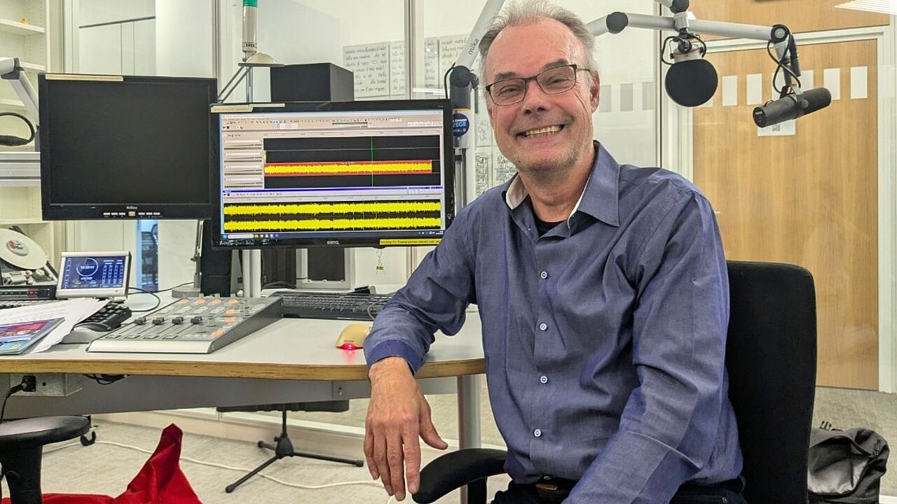 Andreas Goetze lacht in die Kamera, sitzend im Studio.